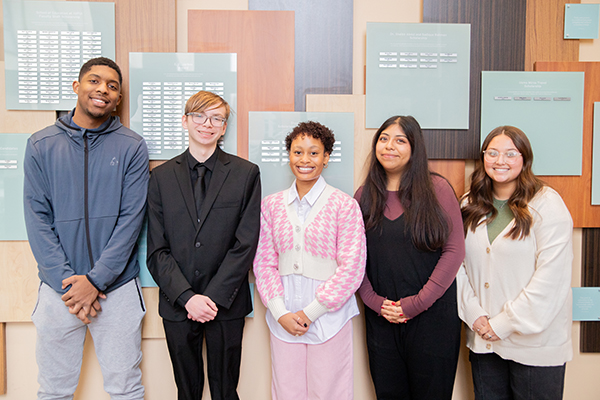 Student ambassadors pose in front of scholarship wall